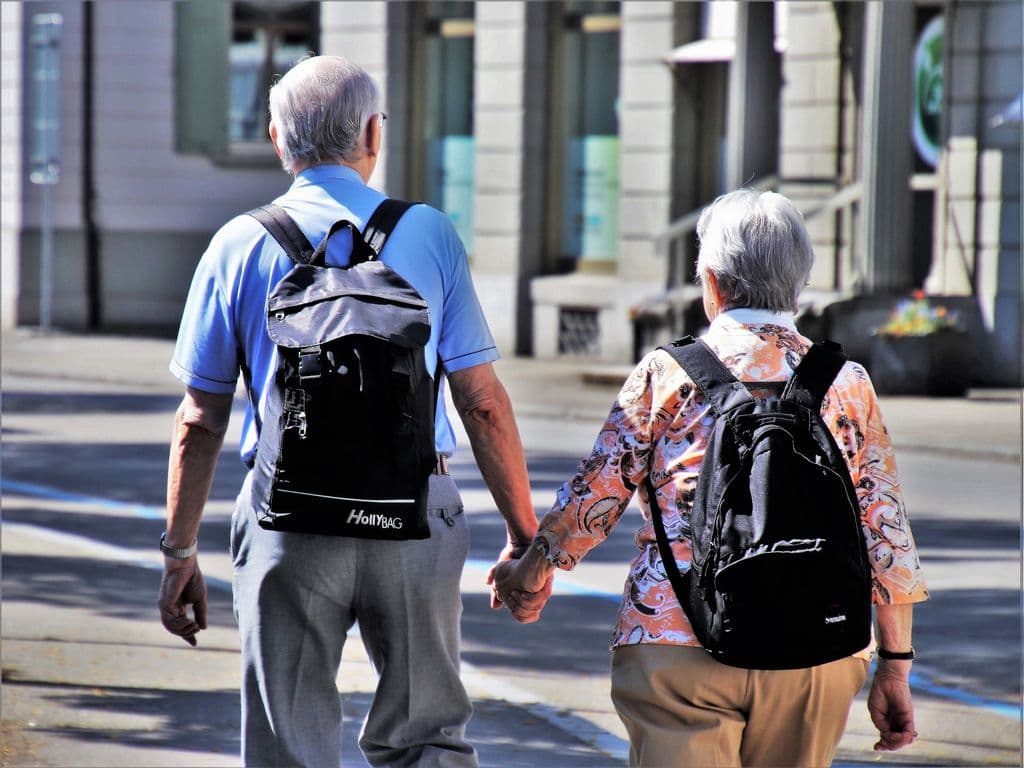 Una pareja de personas mayores caminando de la mano.